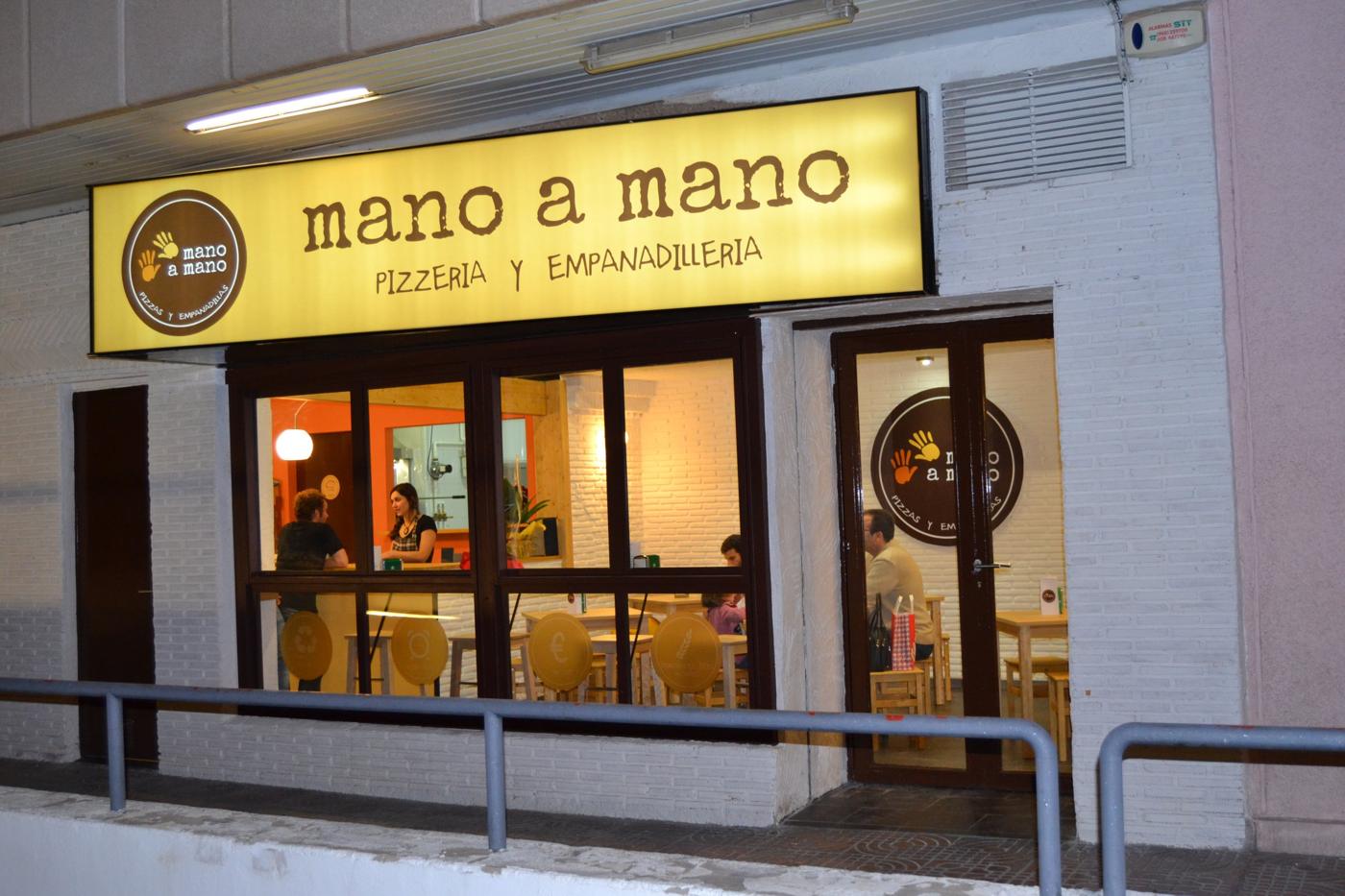Fachada del primer Mano a Mano, con el cartel amarillo de pizzería y empanadillería.